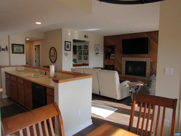 a living room with stainless steel appliances furniture a fireplace and a flat screen tv