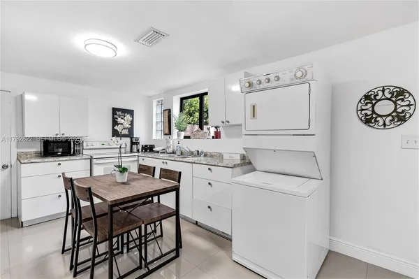 a kitchen with a table chairs and white cabinets