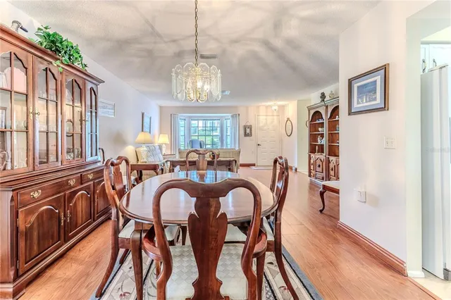 a kitchen with stainless steel appliances granite countertop a stove top oven a sink a dining table and chairs with wooden floor