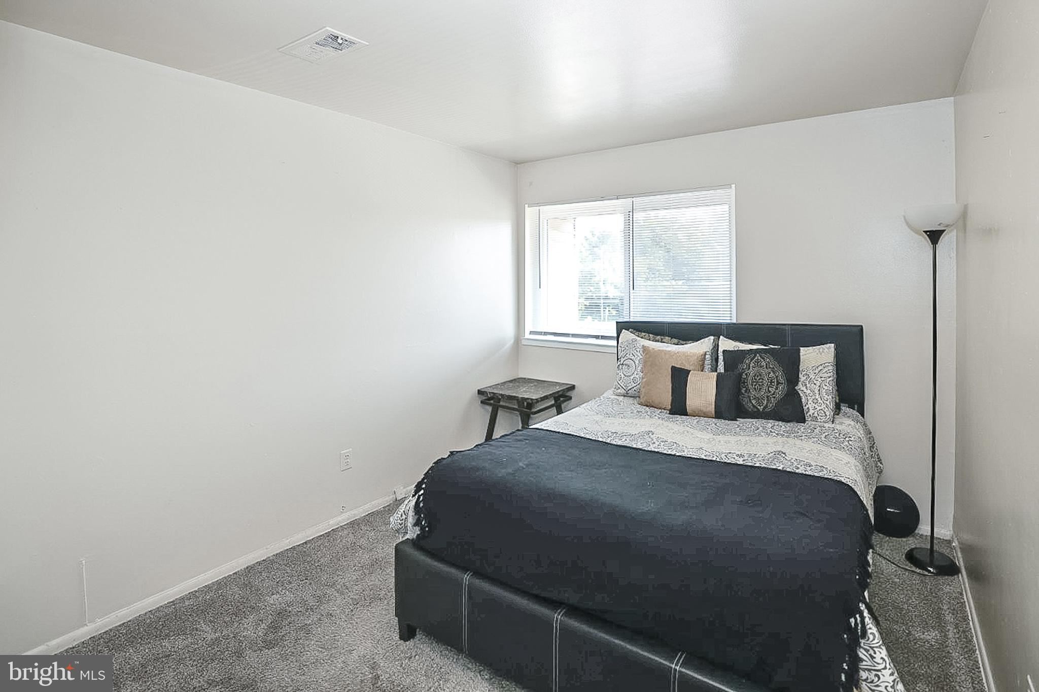 10214 Prince Place, Unit 8202 Upper Marlboro, MD 20774 - Photo 14 of 22 a bed sitting in a bedroom next to a window with a chair