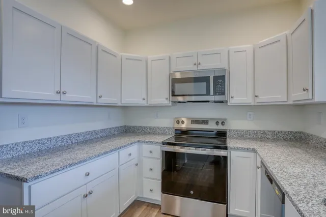a kitchen with granite countertop white cabinets and stainless steel appliances