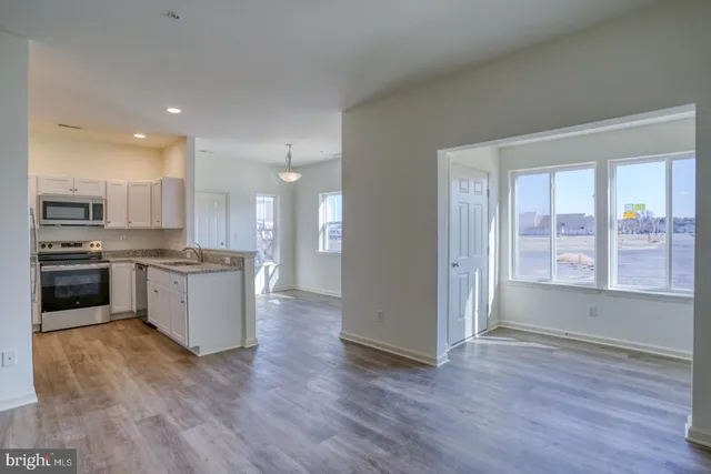 a large kitchen with a large counter top a sink stainless steel appliances and cabinets