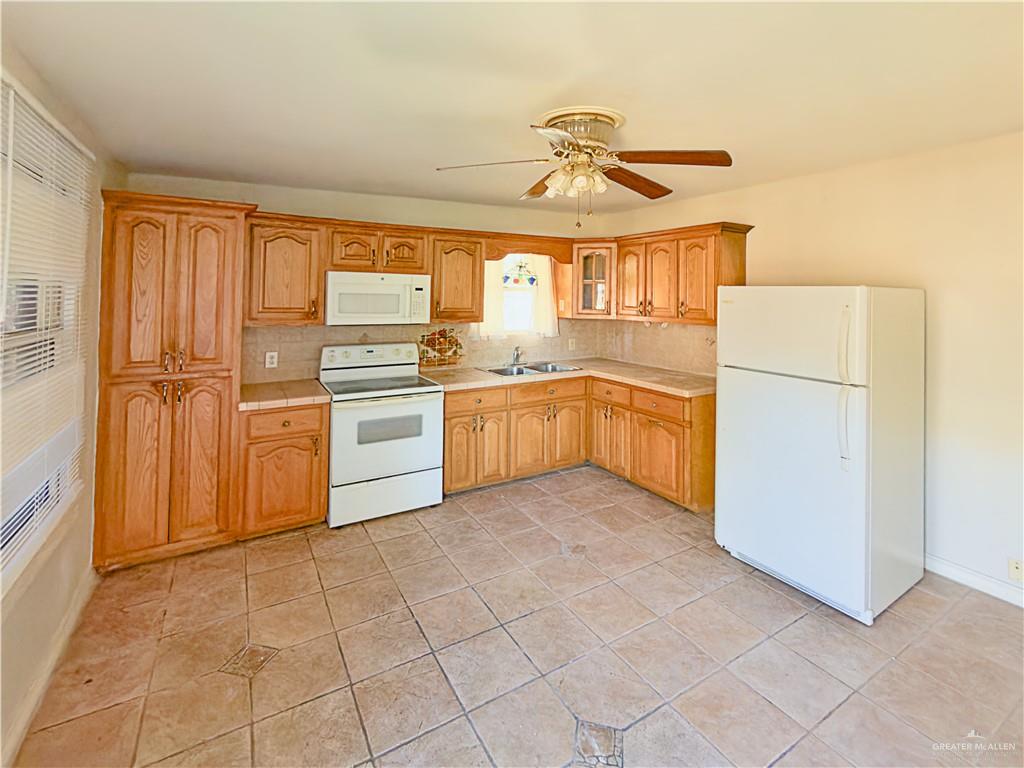 706 West 10th Street Weslaco, TX 78596 - Photo 3 of 14 a kitchen with a refrigerator a stove top oven and cabinets