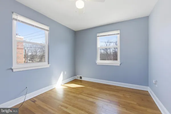 a view of empty room with wooden floor and fan