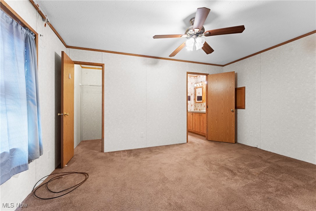 6615 Cleveland Road, Unit K2 Ravenna, OH 44266 - Photo 11 of 24 Unfurnished bedroom with ornamental molding, a ceiling fan, light colored carpet, connected bathroom, and a spacious closet
