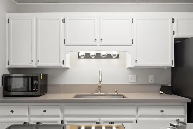 a kitchen with granite countertop white cabinets and stainless steel appliances