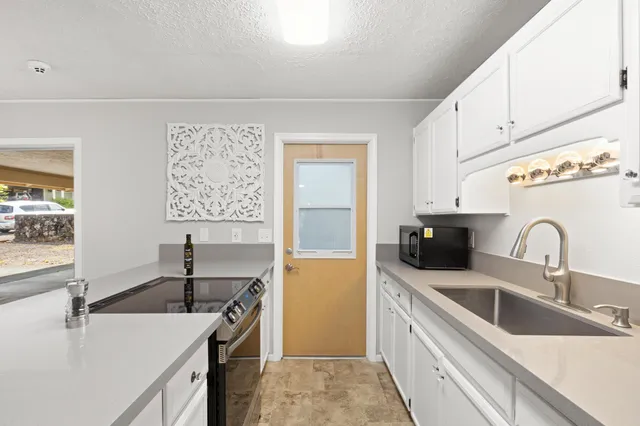a kitchen with a sink and a stove top oven with wooden floor