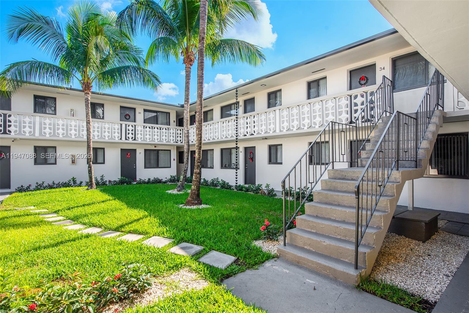 1330 West 29th Street, Unit 35 Hialeah, FL 33012 - Photo 13 of 16 a front view of a house with a garden and trees