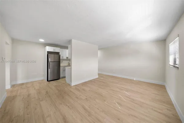 a view of an empty room with wooden floor and a window