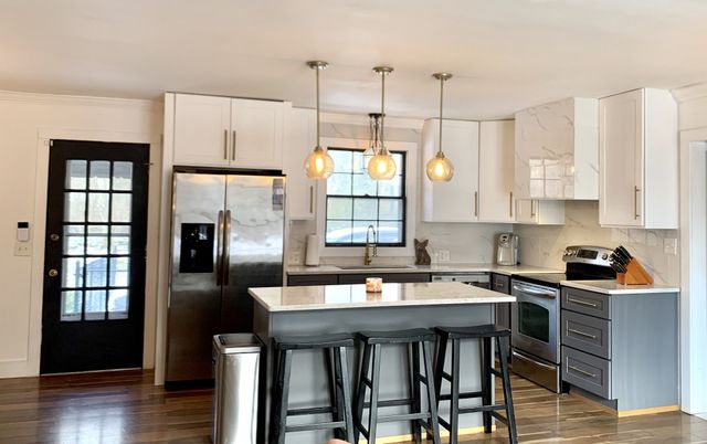 a kitchen with stainless steel appliances granite countertop a refrigerator a sink dishwasher a stove and white cabinets with wooden floor