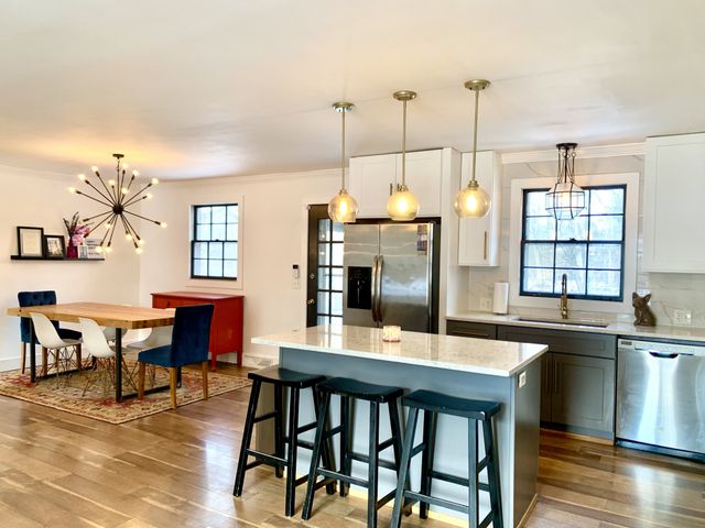 a kitchen with stainless steel appliances kitchen island granite countertop a dining table chairs and sink