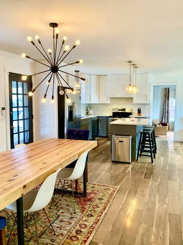 a large kitchen with kitchen island a stove a sink dishwasher and white cabinets with wooden floor