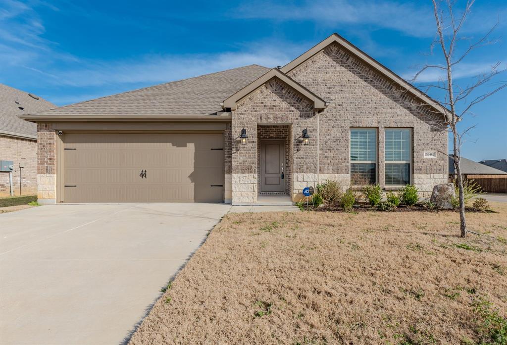 Brick and stone facade residence featuring a two-car garage with decorative hardware, a covered entry with an overhead light fixture, and an additional exterior light fixture illuminating the front