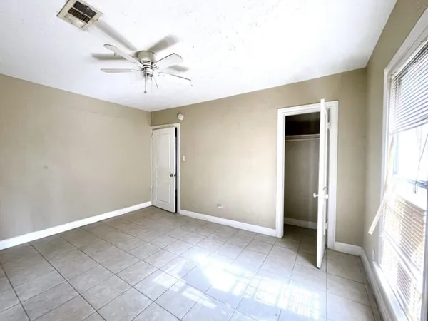 an empty room with windows and fan