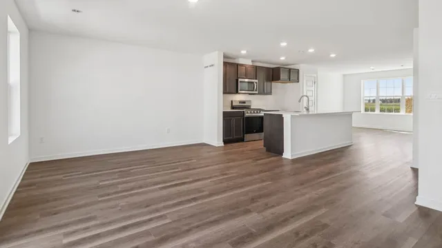 a kitchen with stainless steel appliances kitchen island wooden floors and white walls