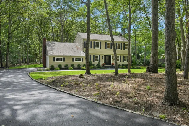 a view of a house with a yard and large tree