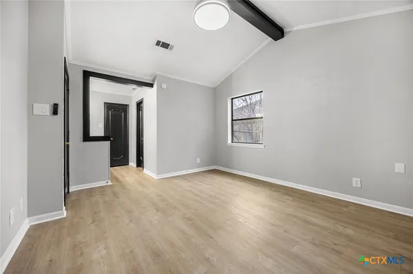 a view of an empty room with wooden floor and a window