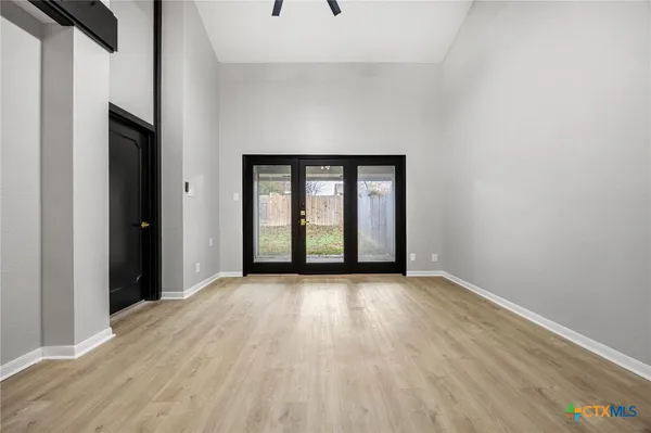 an empty room with wooden floor and windows