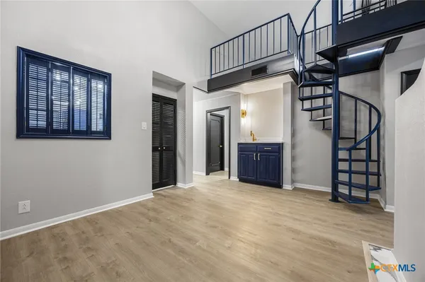 a view of an empty room with wooden floor and stairs