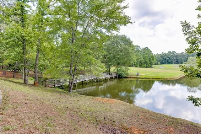a view of a lake with a yard and large trees