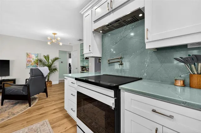 a kitchen with stainless steel appliances granite countertop a sink a stove and a wooden floors