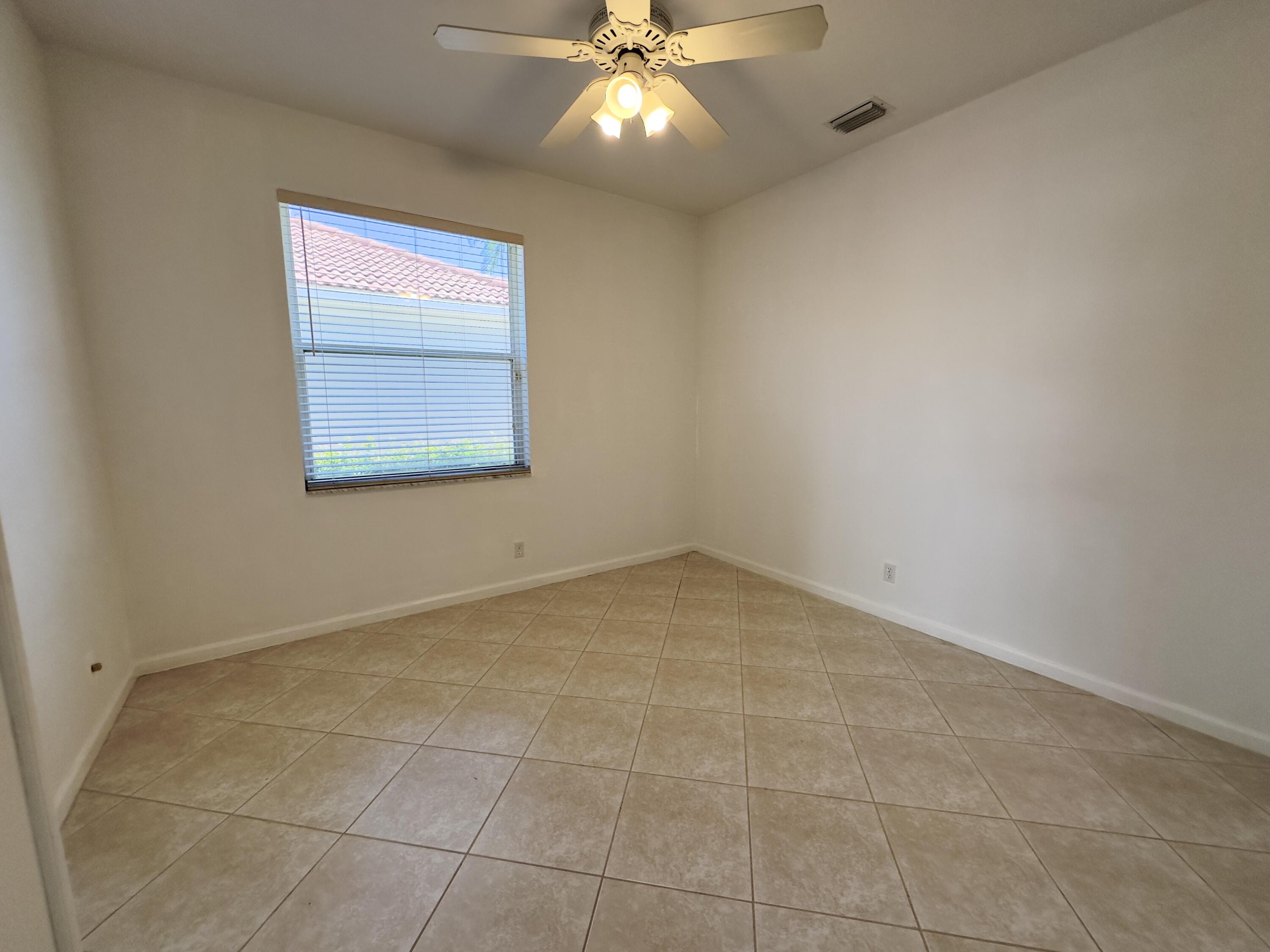 7096 Cataluna Circle Delray Beach, FL 33446 - Photo 14 of 32 an empty room with a chandelier fan and windows