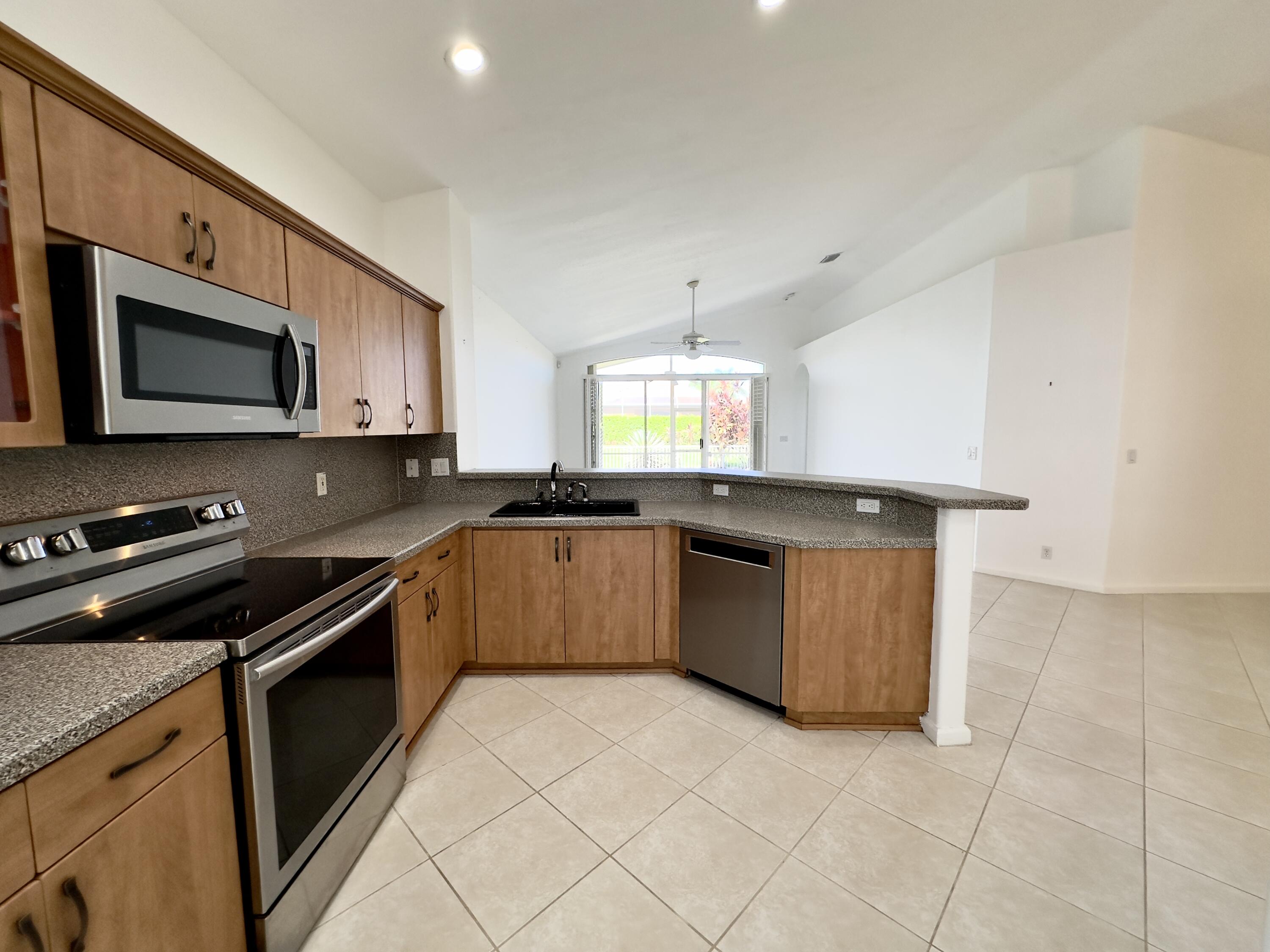 7096 Cataluna Circle Delray Beach, FL 33446 - Photo 18 of 32 a kitchen with stainless steel appliances granite countertop a sink a stove a microwave a counter top space