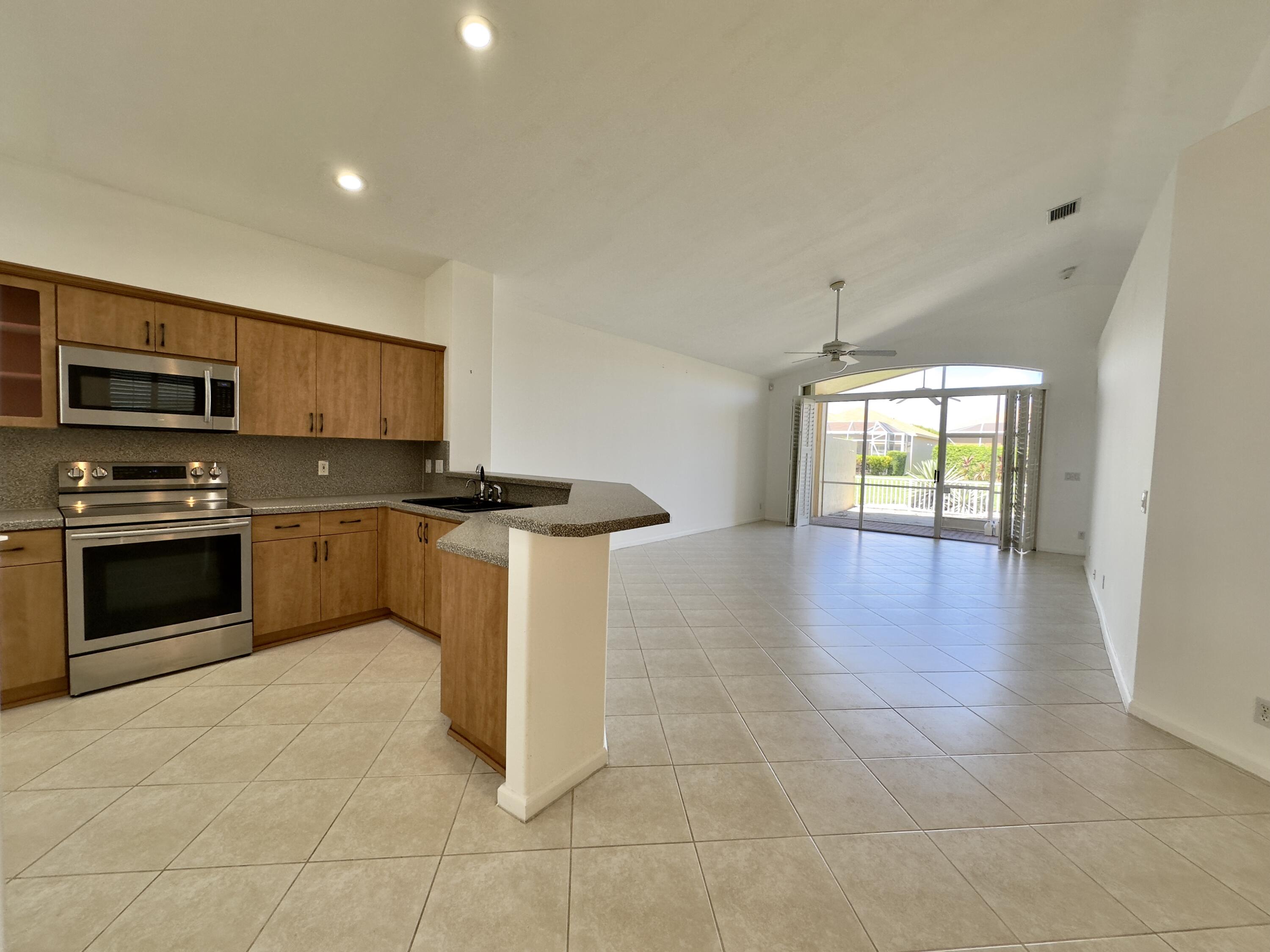 7096 Cataluna Circle Delray Beach, FL 33446 - Photo 2 of 32 a kitchen with granite countertop a stove a sink and a microwave