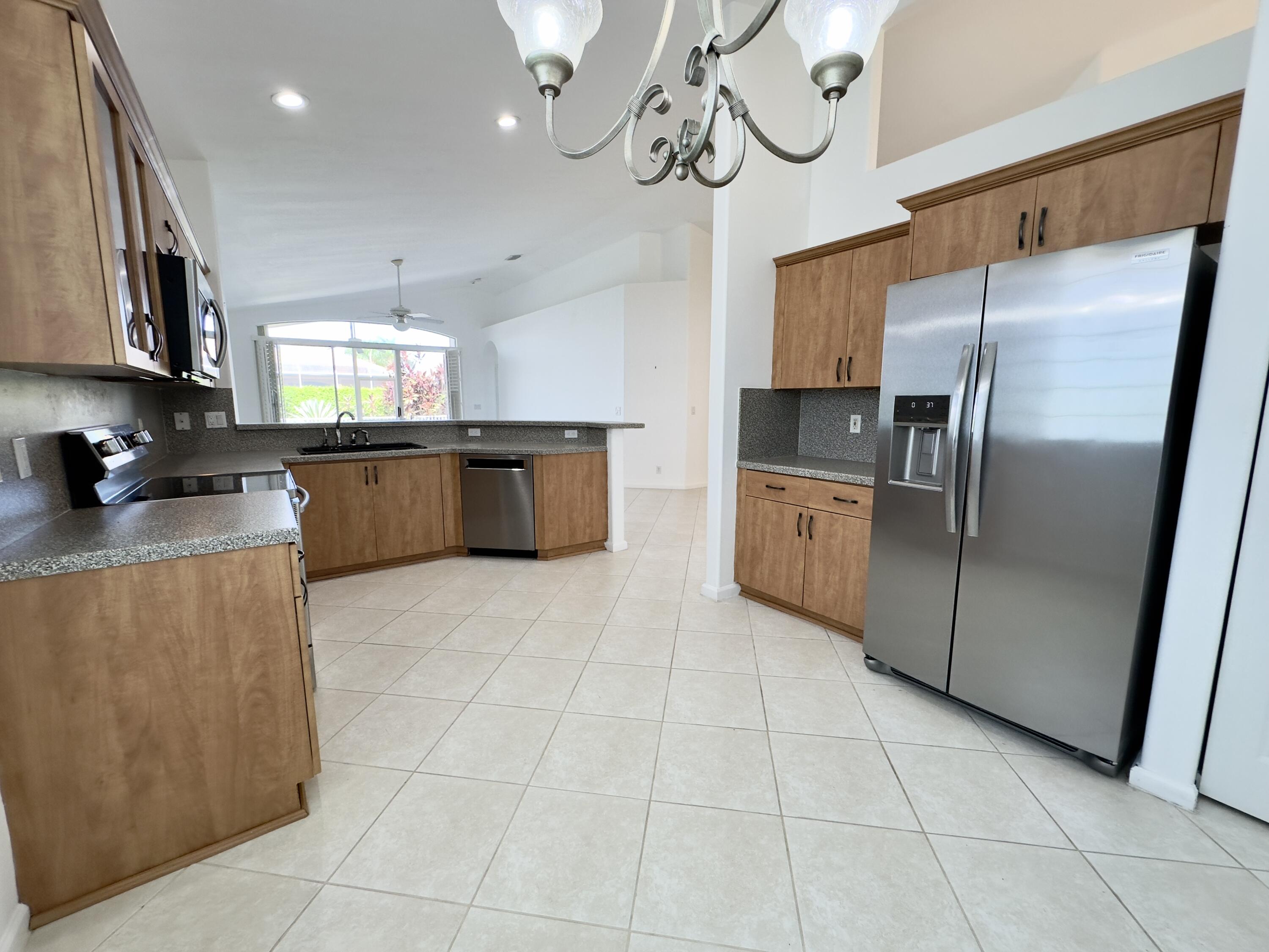 7096 Cataluna Circle Delray Beach, FL 33446 - Photo 3 of 32 a kitchen with stainless steel appliances granite countertop a refrigerator a sink a stove top oven and a counter top space
