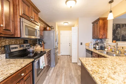 a kitchen with stainless steel appliances granite countertop a sink stove and refrigerator