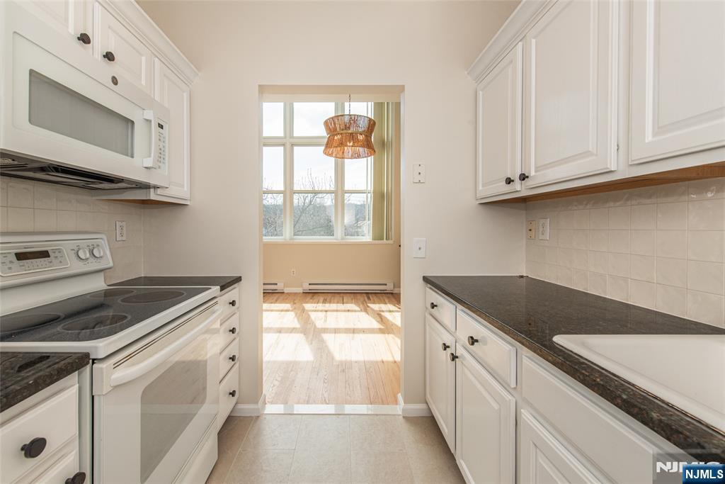 280 Main Street, Unit 305 Little Falls, NJ 07424 - Photo 11 of 24 a kitchen with granite countertop white cabinets and a stove