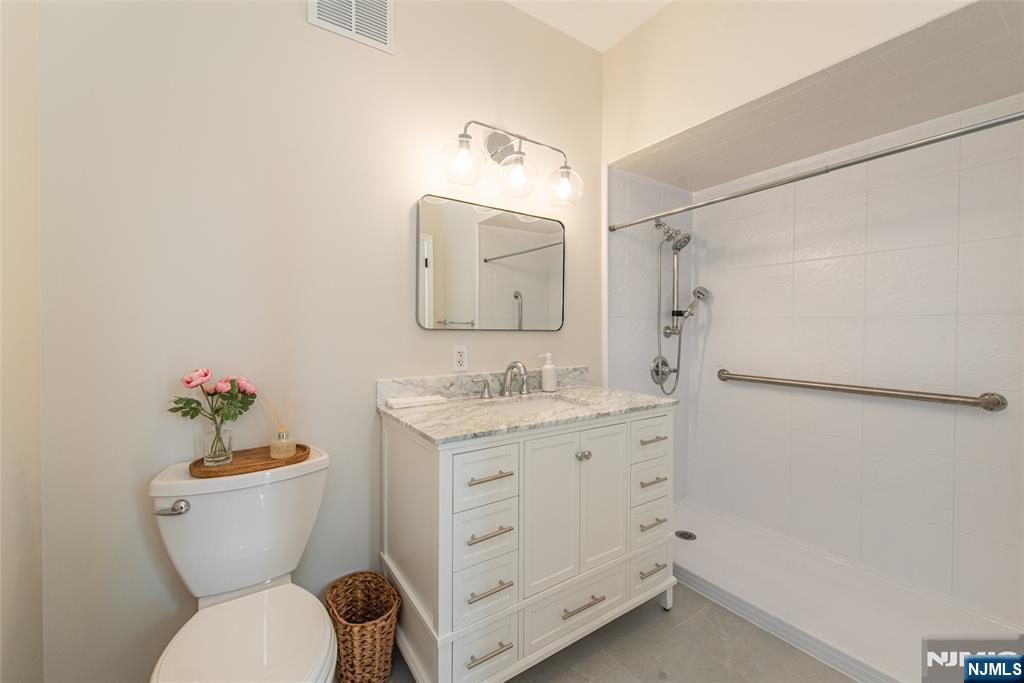 280 Main Street, Unit 305 Little Falls, NJ 07424 - Photo 15 of 24 a bathroom with a granite countertop toilet sink and mirror