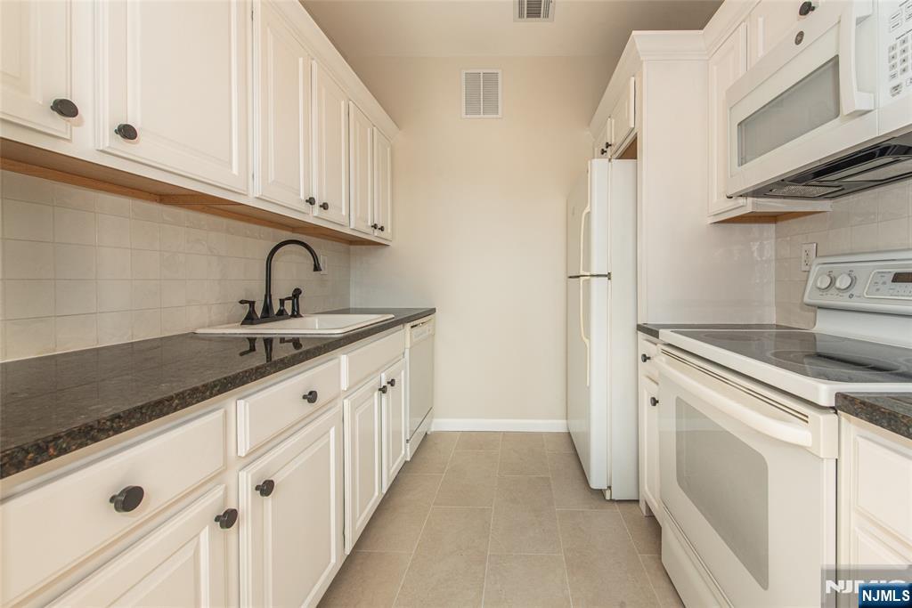 280 Main Street, Unit 305 Little Falls, NJ 07424 - Photo 8 of 24 a kitchen with granite countertop white cabinets and white appliances
