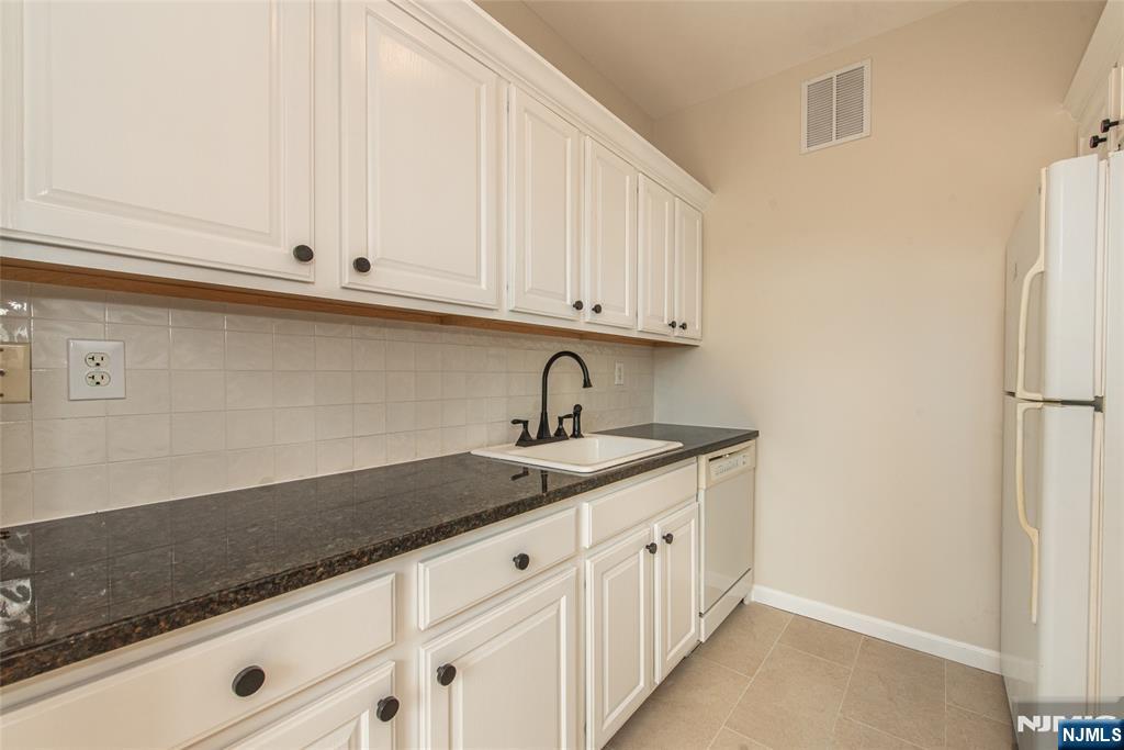 280 Main Street, Unit 305 Little Falls, NJ 07424 - Photo 9 of 24 a kitchen with granite countertop white cabinets and sink