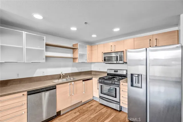 a kitchen with stainless steel appliances granite countertop a refrigerator a sink and a stove