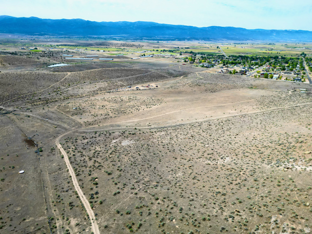 600 East E Street Moroni, UT 84646 - Photo 19 of 38 Expansive desert landscape featuring scattered brush, visible dirt paths, and distant mountain ranges