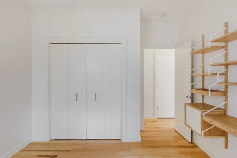 a view of a bedroom with wooden floor and cabinet