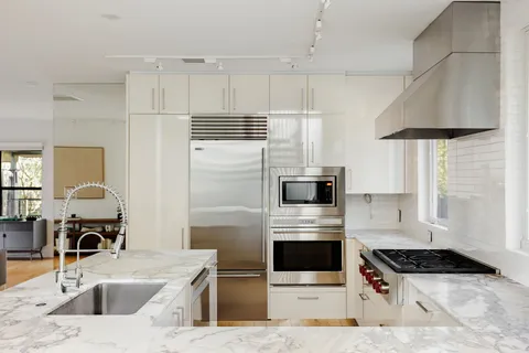 a kitchen with stainless steel appliances kitchen island granite countertop a sink a stove and a refrigerator