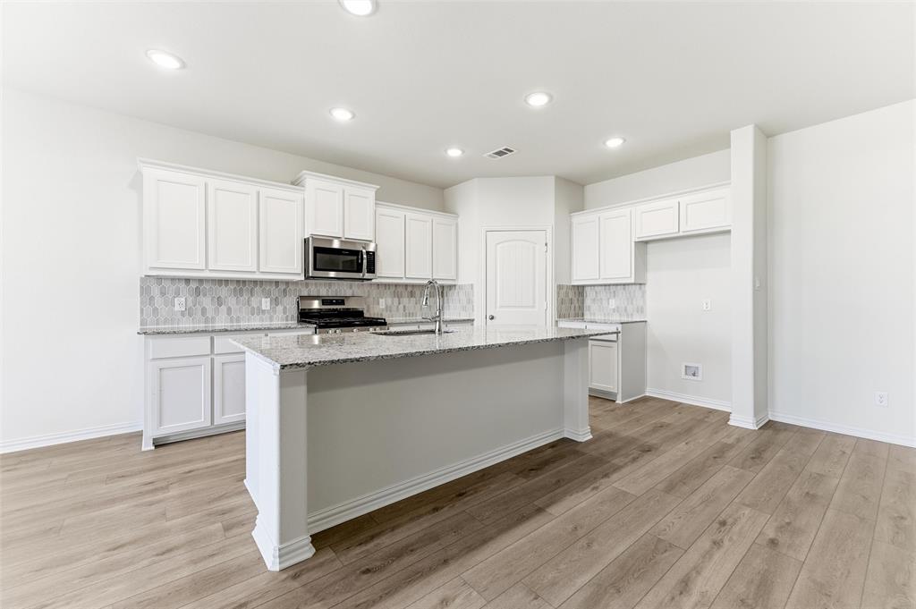 3513 Helena Street Gainesville, TX 76240 - Photo 12 of 25 a kitchen with granite countertop white cabinets and stainless steel appliances