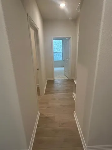a view of a hallway with wooden floor and closet