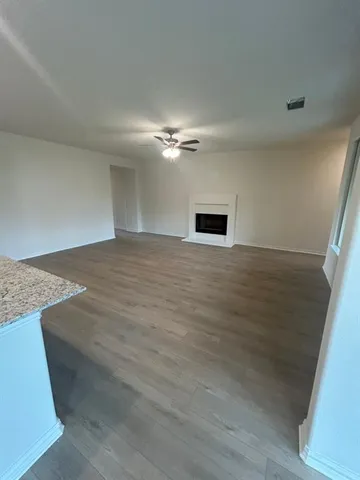 a view of an empty room with a ceiling fan and window