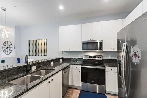 a kitchen with granite countertop a sink stainless steel appliances and cabinets