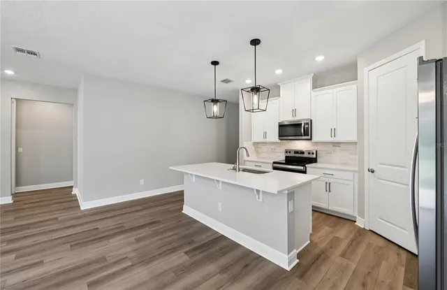 a kitchen with stainless steel appliances a stove top oven a sink cabinets and a wooden floor