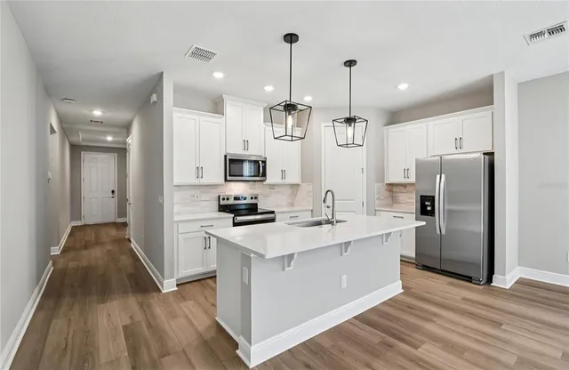 a kitchen with stainless steel appliances a stove top oven a refrigerator a sink and dishwasher with wooden floor