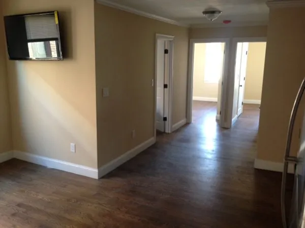 an empty room with wooden floor and windows