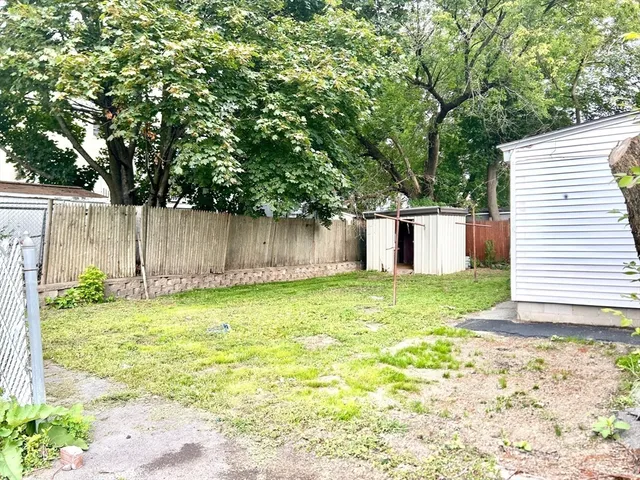 a view of a backyard with large tree and wooden fence
