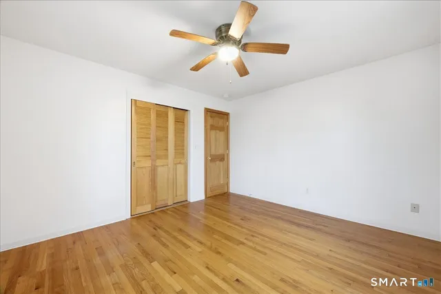 an empty room with wooden floor and ceiling fan