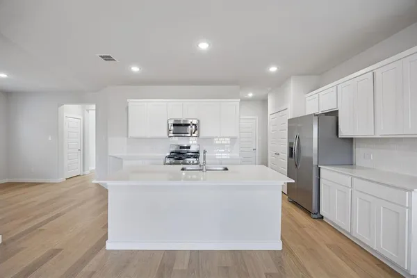 a large white kitchen with stainless steel appliances