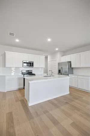a large white kitchen with kitchen island sink and white cabinets