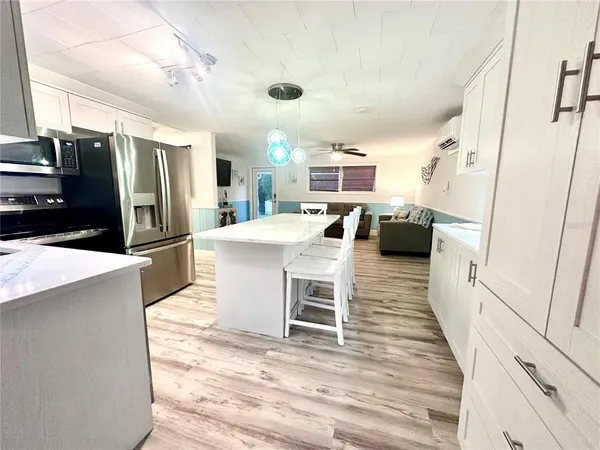 a kitchen with stainless steel appliances a refrigerator a stove a sink dishwasher and white cabinets with wooden floor